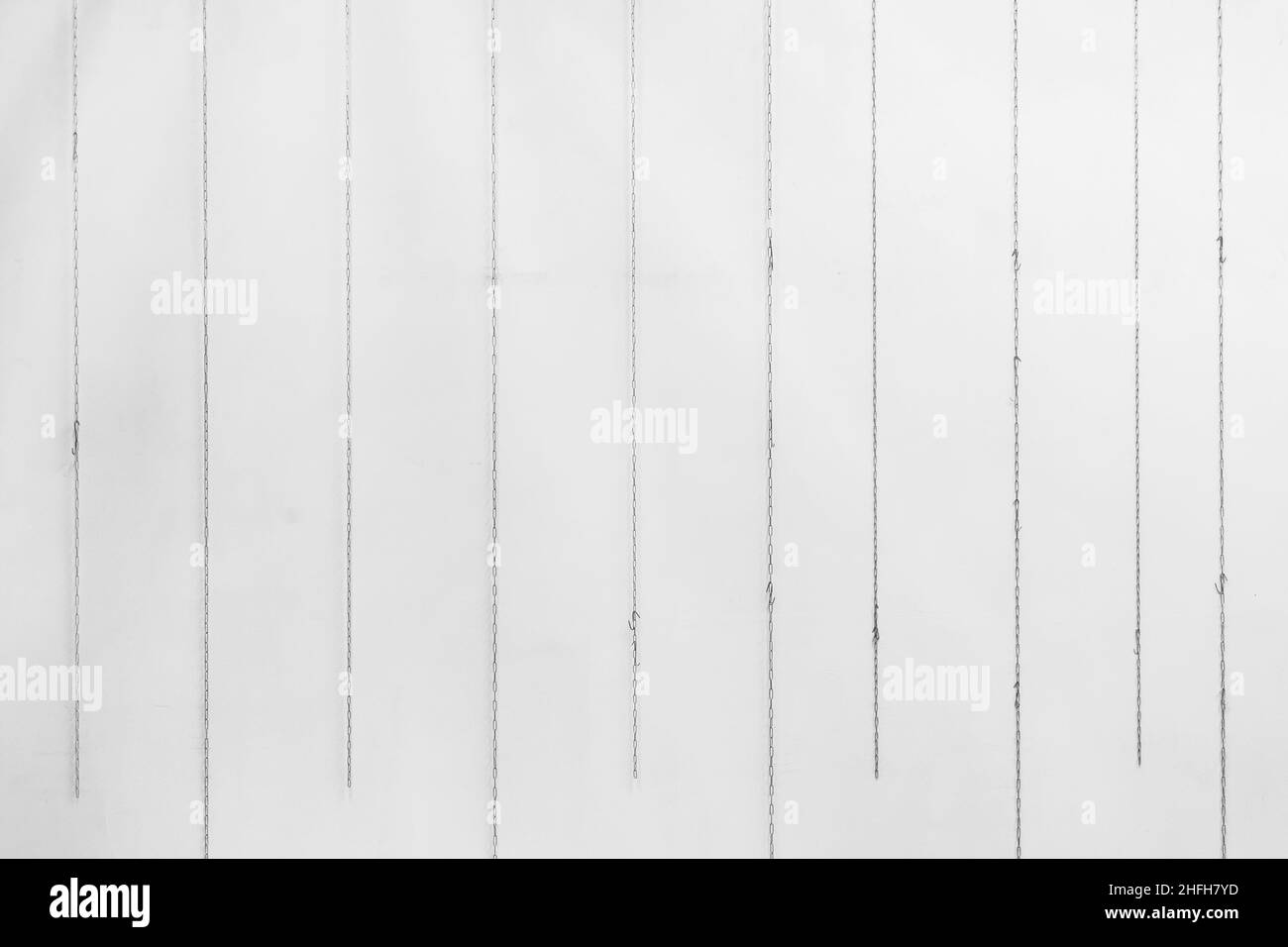 Ketten hängen vor dem Hintergrund der weißen Wanddekoration Dekor abstrakten Hintergrund des Innenraums. Stockfoto
