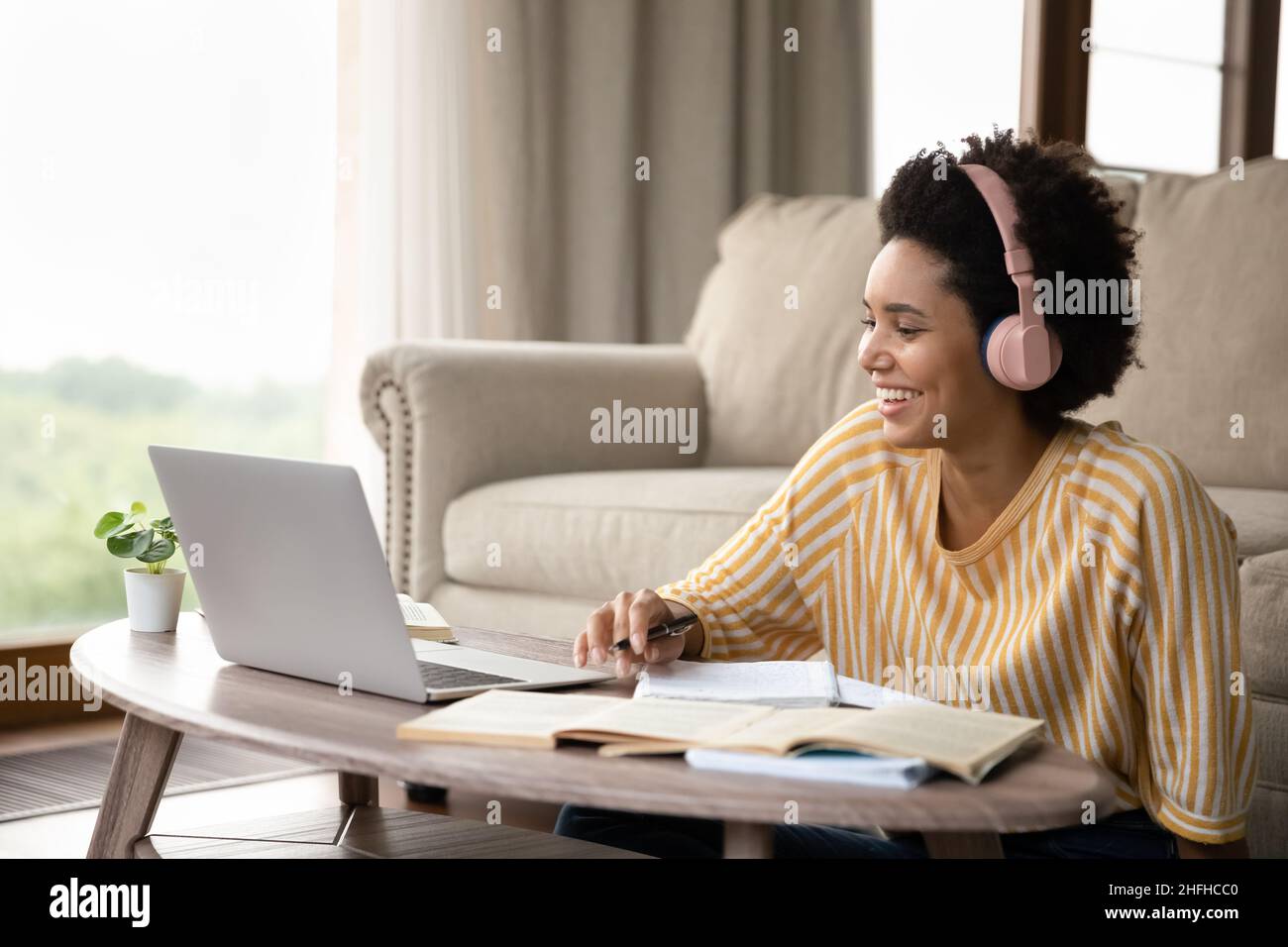 Lächelnde, tausendjährige afroamerikanische Frau, die aus der Ferne studiert. Stockfoto