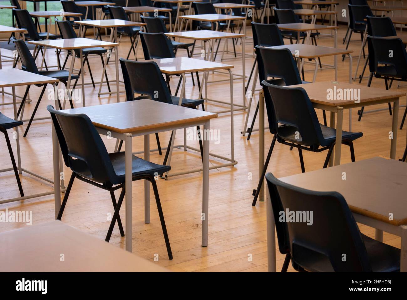 Schulstühle und -Tische für Prüfungen in einer Schulhalle. Frühe Vorbereitung auf Untersuchungen in einem Prüfungsraum Stockfoto