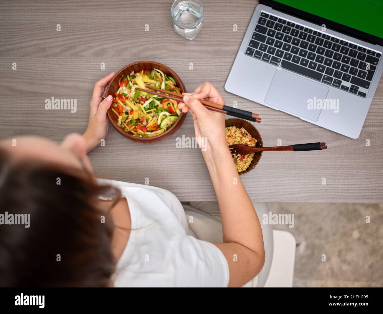 Draufsicht auf eine Frau, die mit Essstäbchen vor dem Computer isst Stockfoto