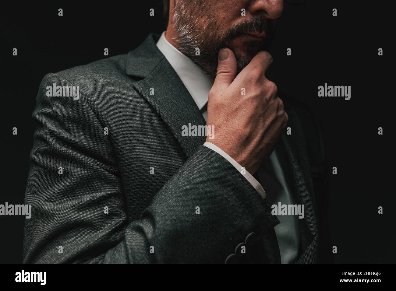 Überlegungen vor der Gründung eines Unternehmens, elegante Geschäftsmann in grauem Anzug denken und planen, Low-Key-Porträt mit selektivem Fokus Stockfoto
