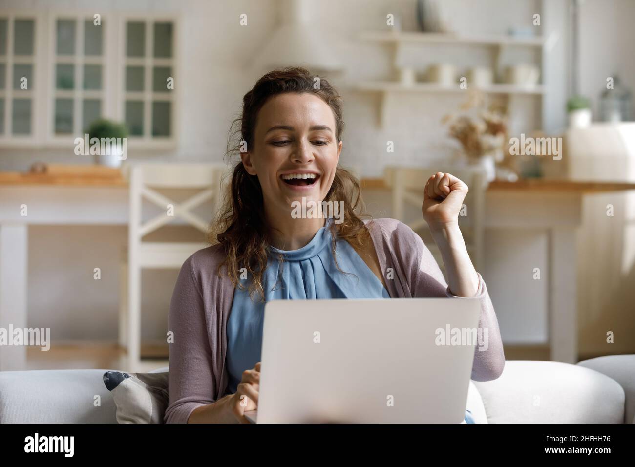 Fröhlich lachende junge Frau feiert Erfolg im Internet. Stockfoto