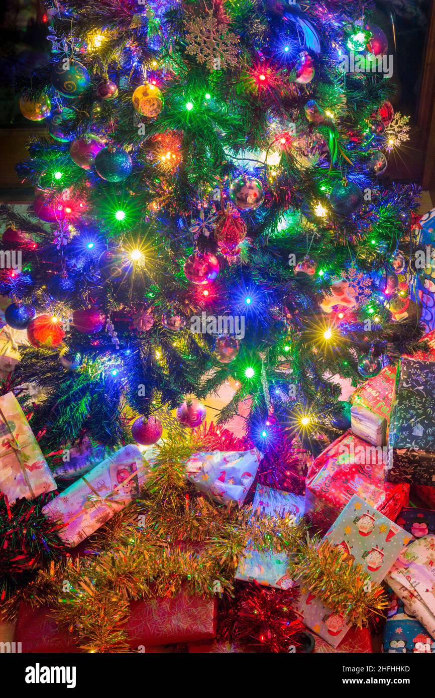 Eingewickelte Weihnachtsgeschenke unter einem künstlichen Weihnachtsbaum. Stockfoto