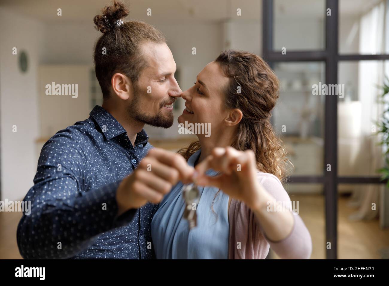 Glückliches Millennial Familienpaar zeigt Schlüssel zur Kamera. Stockfoto