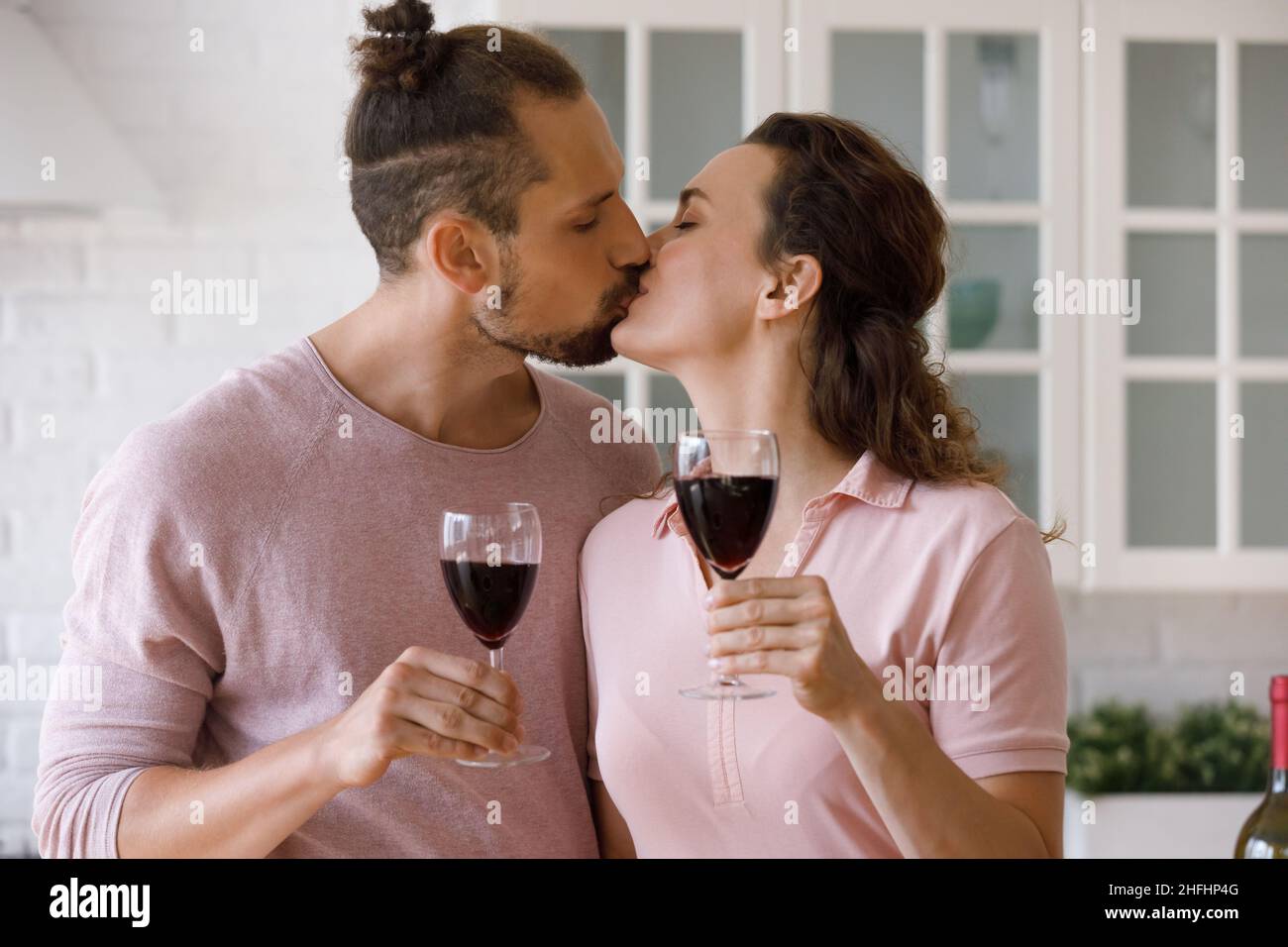 Liebevoll liebevolles junges Familienpaar küsst, klirrende Gläser. Stockfoto