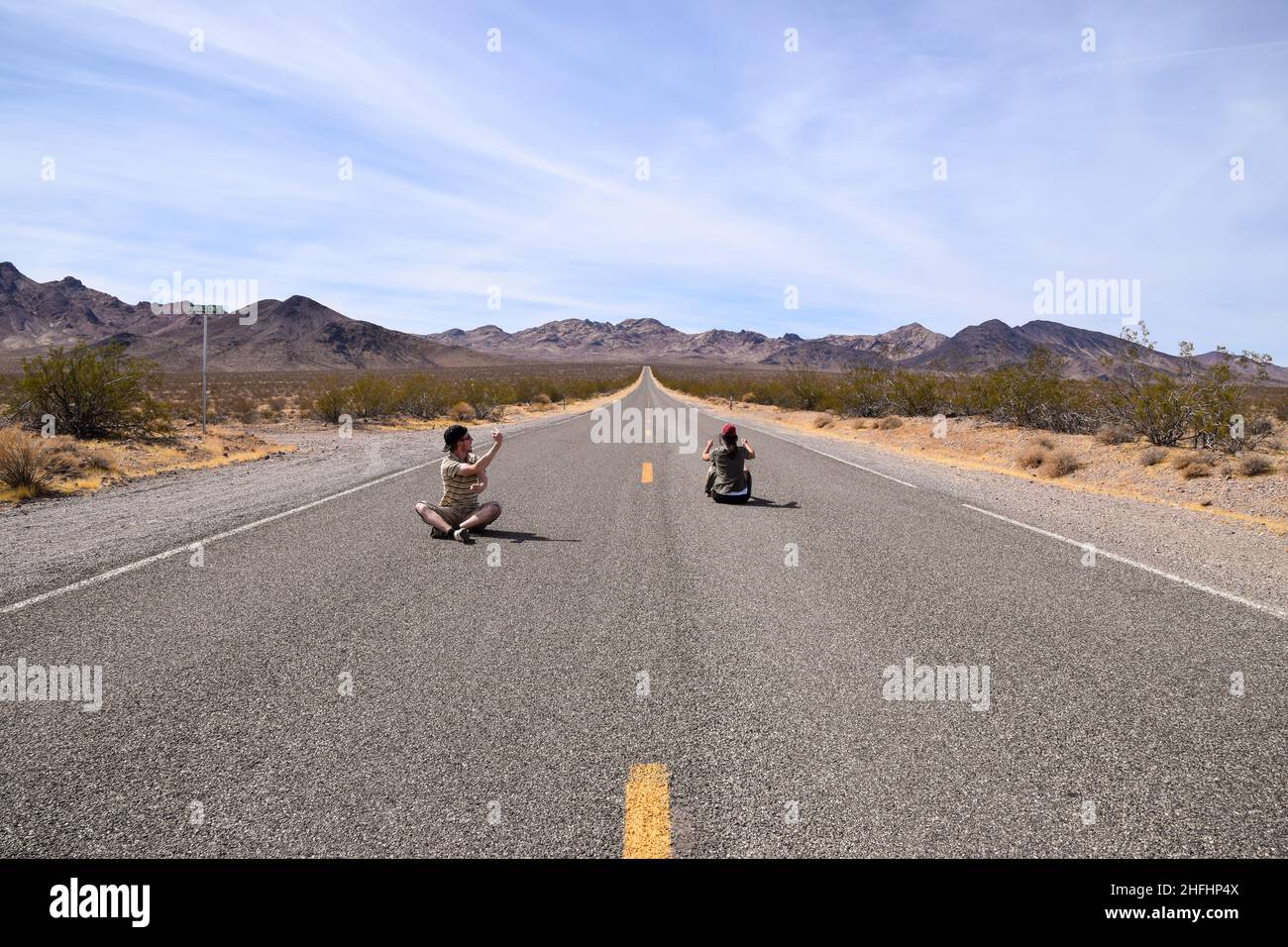 Zwei Menschen geben vor, auf einer Autobahn im Death Valley, USA, zu fahren Stockfoto