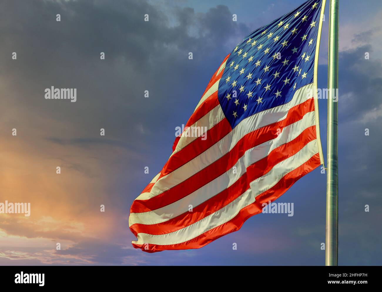 Die Flagge der Vereinigten Staaten von Amerika wird gegen den Sonnenuntergang am Himmel geschwenkt Stockfoto