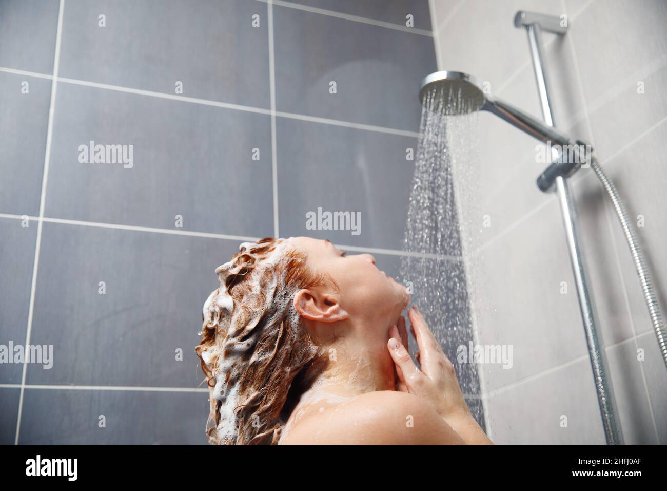 Rückansicht einer Frau, die im Badezimmer duscht. Stockfoto