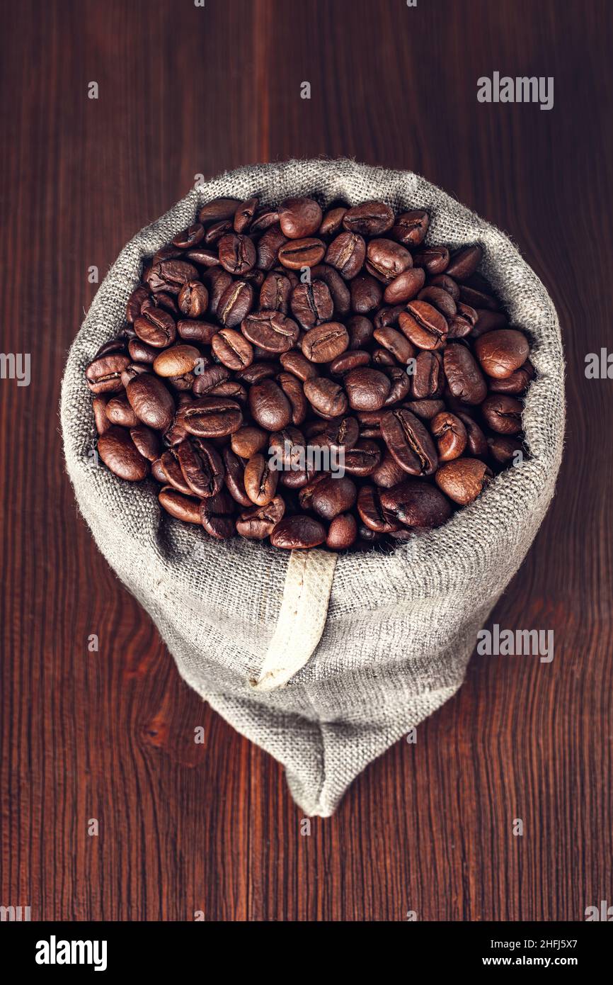 Sackleinen mit Kaffeebohnen auf Holzhintergrund Stockfoto