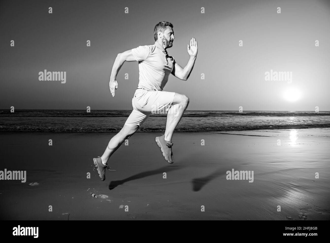 Sportlicher Mann Läufer läuft im Sommer am Strand. Attraktiv fit Mann laufen bei Sonnenuntergang Licht, Training im Freien, Joggen mit erstaunlichen Sonnenuntergang auf dem Hintergrund. Stockfoto