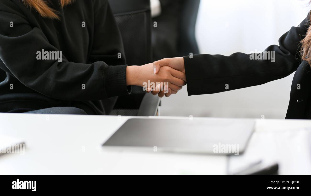 Geschäftsfrauen schütteln sich im Büro die Hände. Geschäftspartner, Geschäfte, Kooperationskonzepte, Herzlichen Glückwunsch.-Nahaufnahme Stockfoto