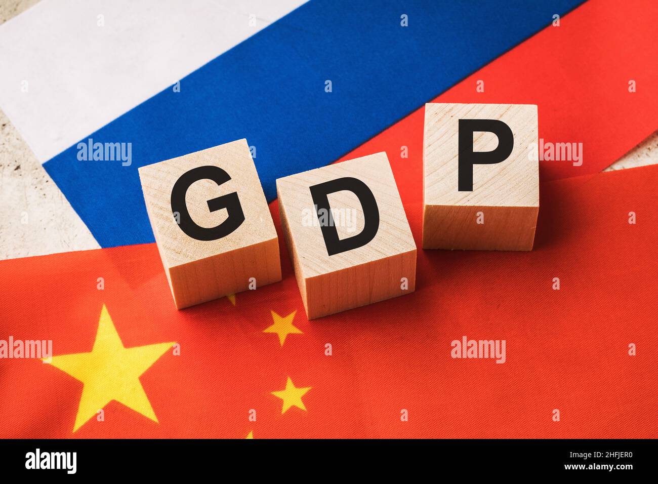 Holzwürfel mit Text auf dem Hintergrund der Flaggen, Konzept zum Thema der Vergleich des BIP von Russland und China Stockfoto