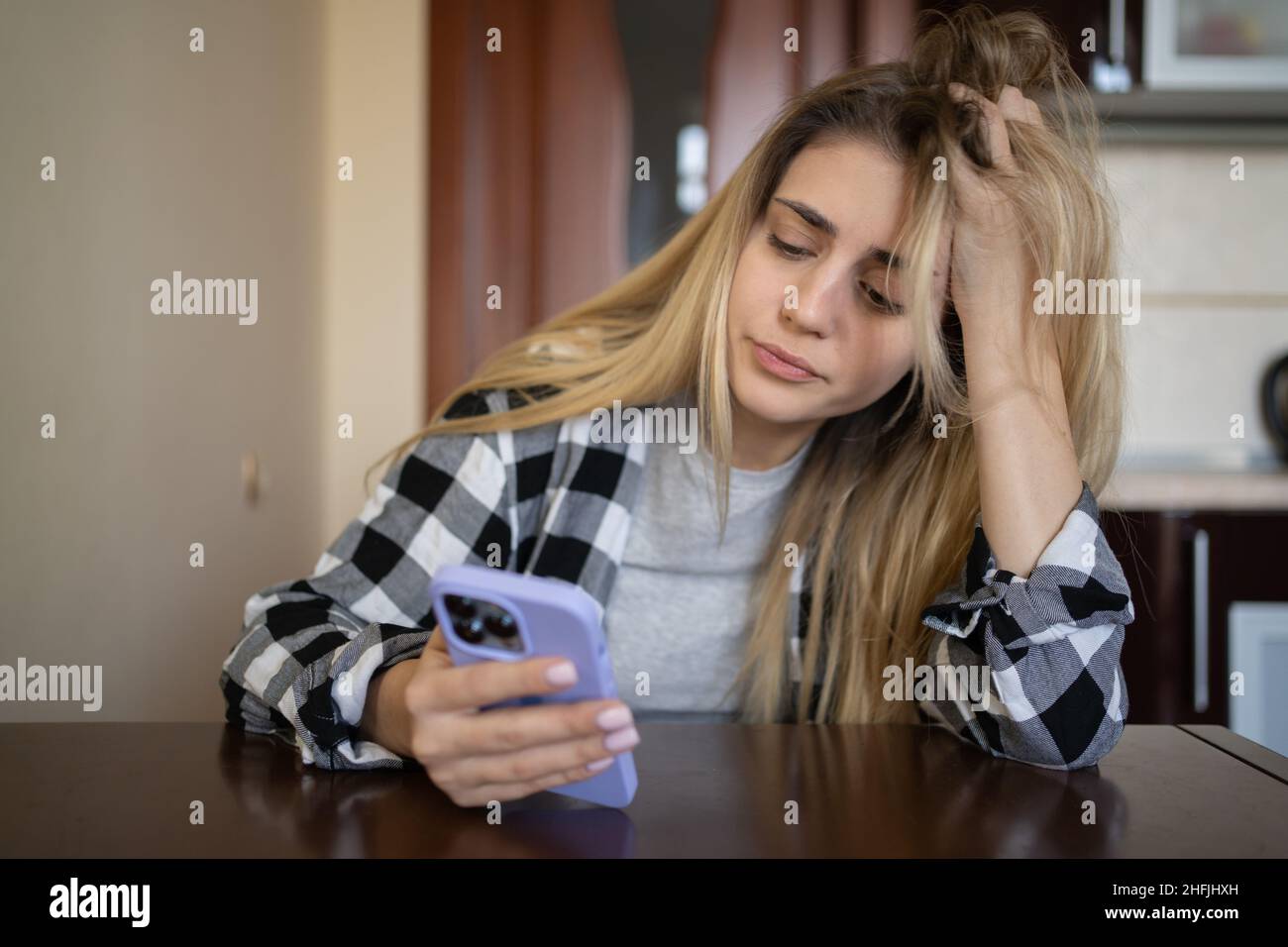 Einsames trauriges Mädchen wartet auf einen Anruf, sitzt zu Hause am Tisch. Deprimiert. Platz kopieren. Stockfoto