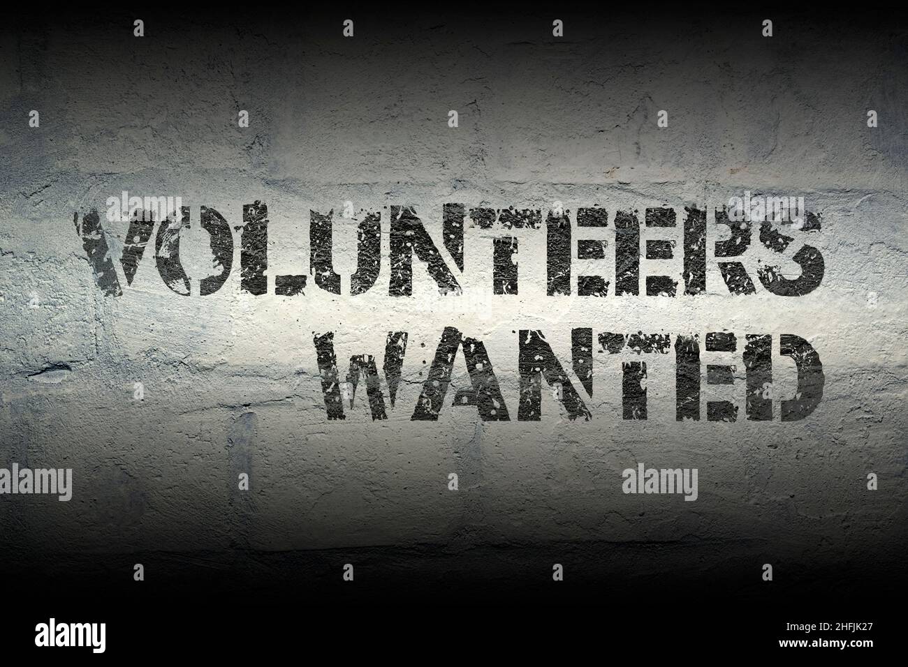Freiwillige wollten einen Ausrufeschablonendruck auf der grunge weißen Ziegelwand Stockfoto