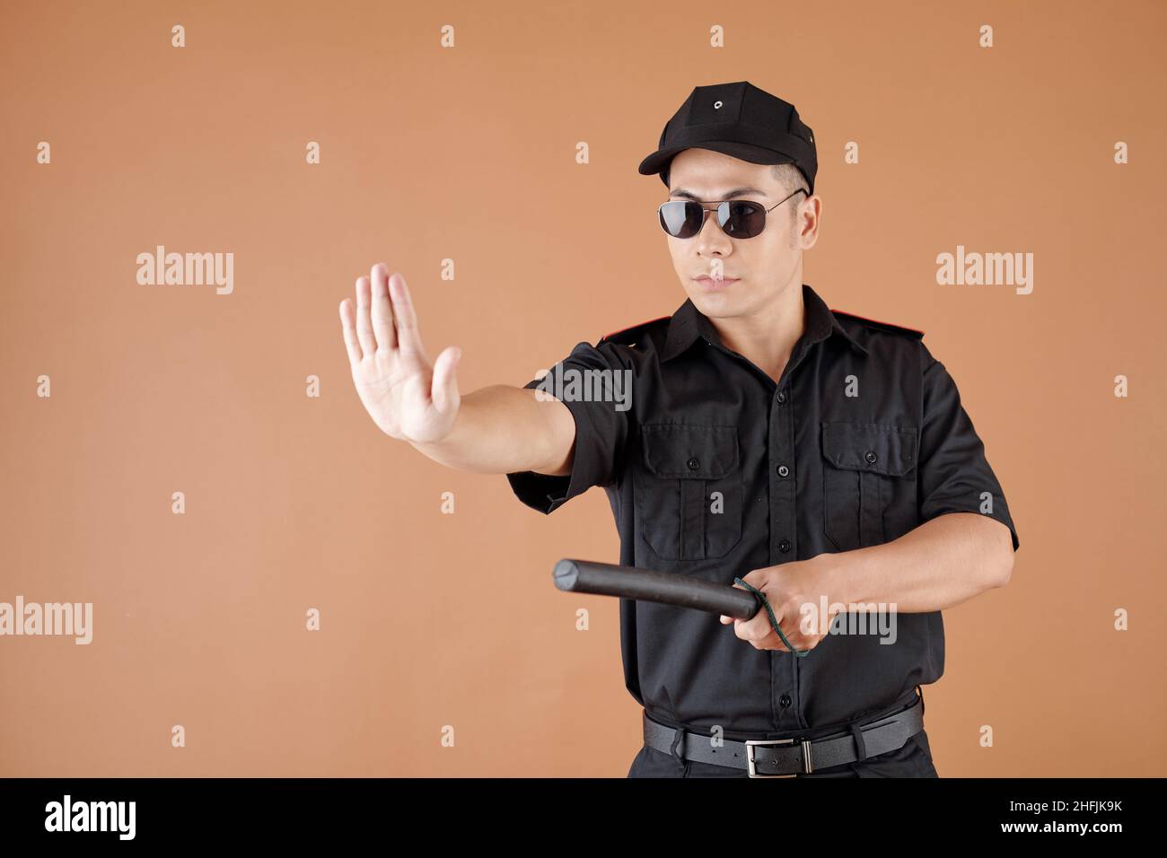 Polizeibeamter macht eine Stoppgeste und droht mit einem Schlagstock Stockfoto