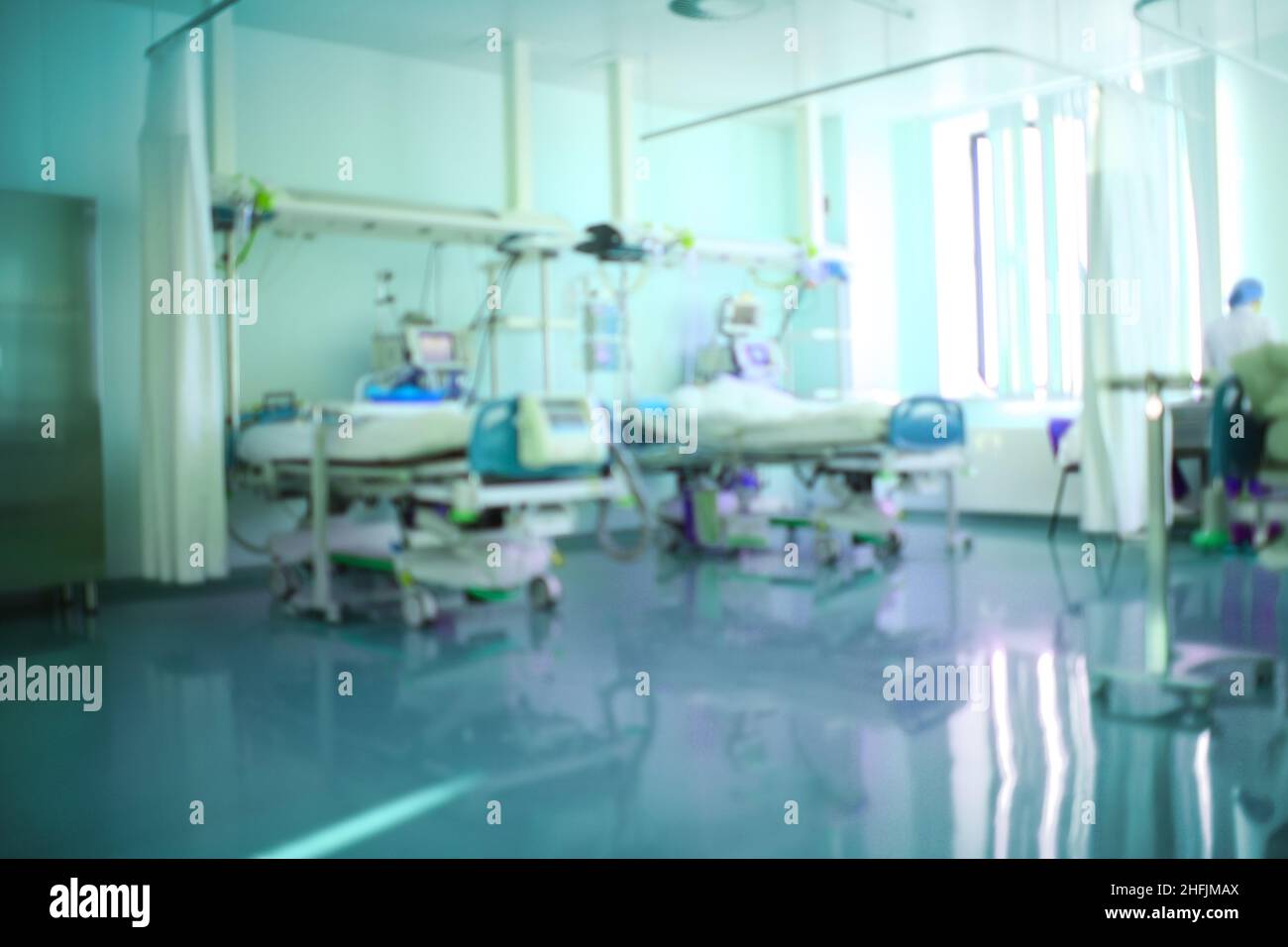 Blick auf die Intensivstation mit technischer Ausstattung und verschwommener Silhouette des Mediziners, unfokussierter Hintergrund. Stockfoto
