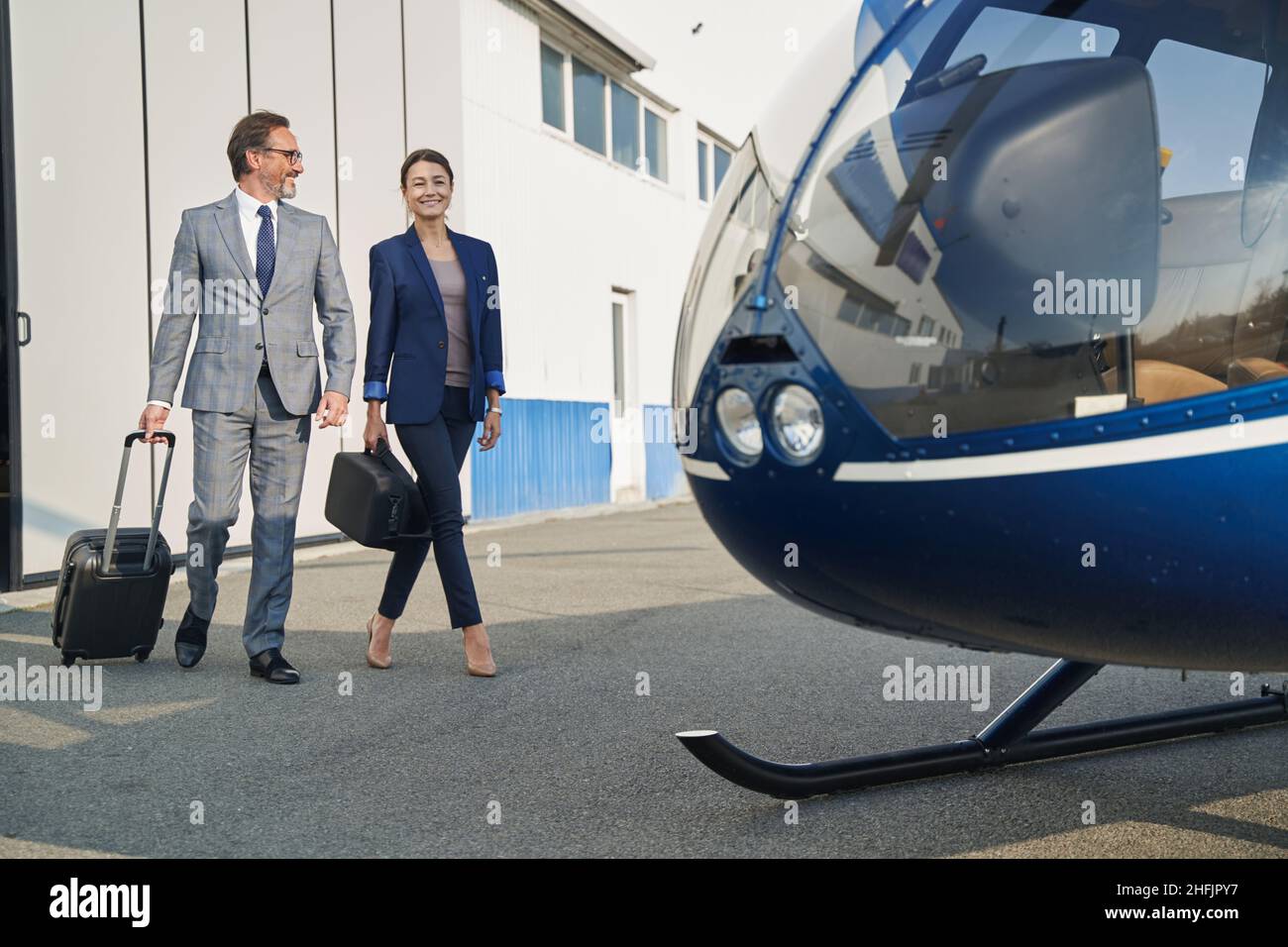 Geschäftsmann und Geschäftsfrau nähern sich Drehflügelflugzeugen auf dem Hubschrauberlandeplatz Stockfoto