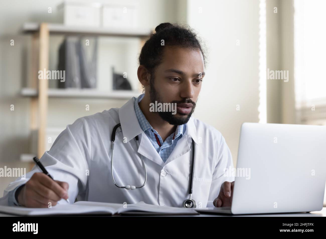 Fokussierter junger afroamerikanischer Arzt, der im Büro arbeitet. Stockfoto