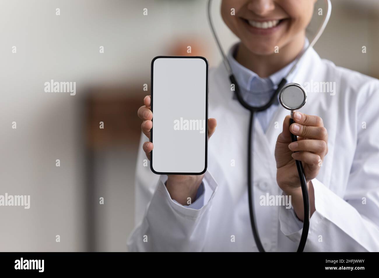 Nahaufnahme lächelnder junger indischer Arzt, der mobile Apps für das Gesundheitswesen anwirbt. Stockfoto