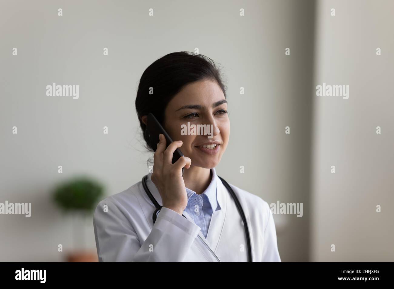 Glücklicher junger indischer Arzt, der ein Handygespräch führt. Stockfoto