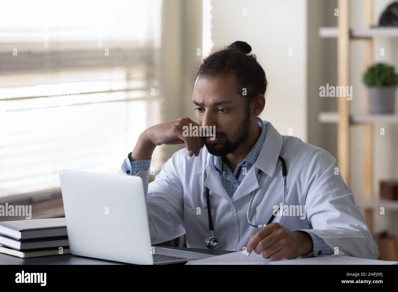 Betont junger afroamerikanischer Arzt, der an eine Problemlösung denkt. Stockfoto