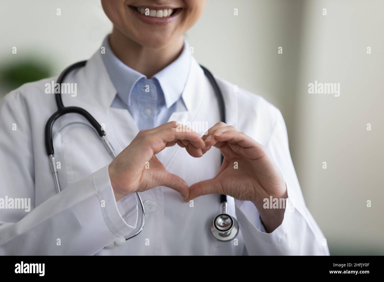 Nahaufnahme glücklicher junger indischer Arzt, der eine Herzgeste macht. Stockfoto
