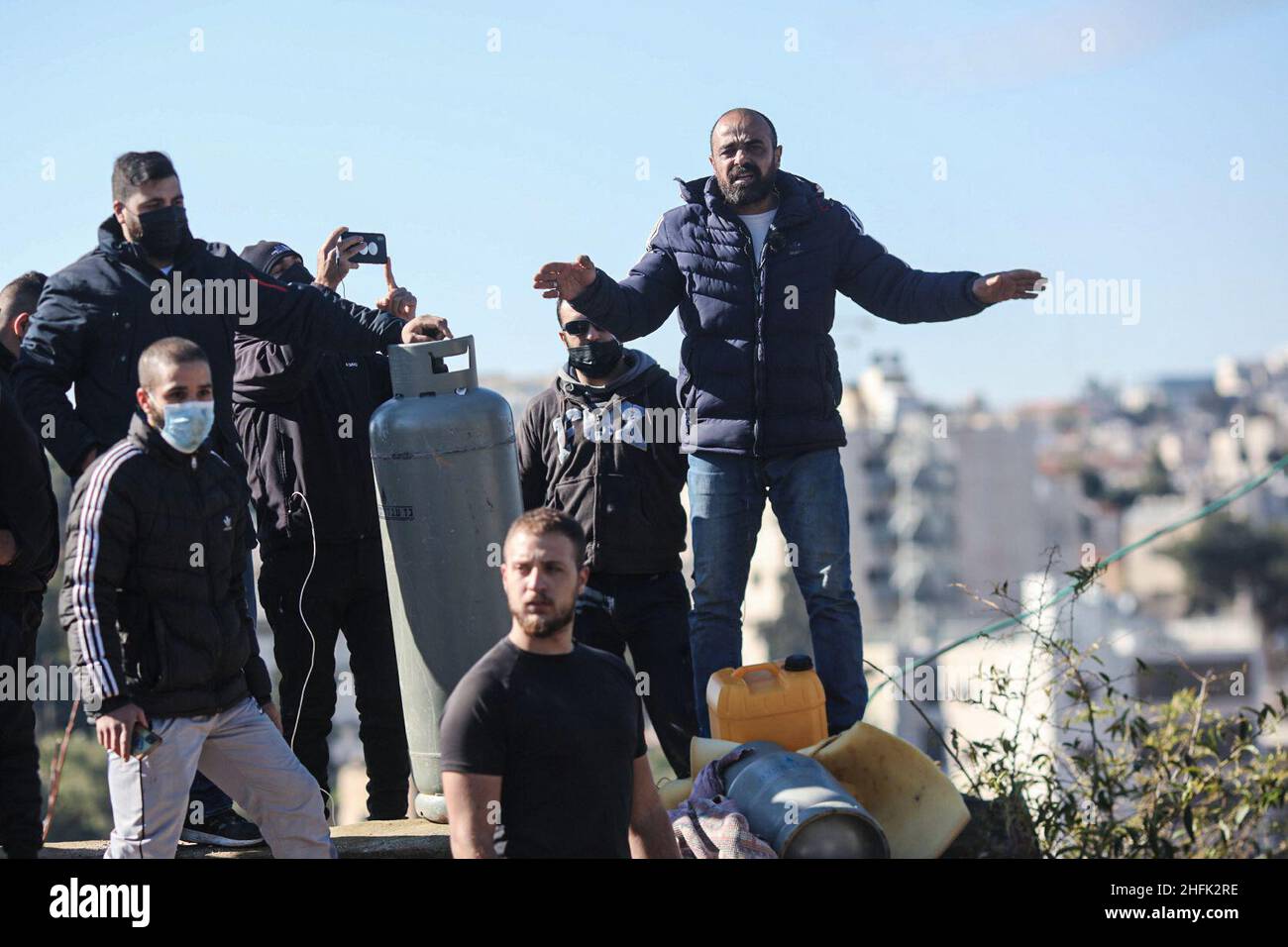 Jerusalem, Israel. 17th Januar 2022. Mitglieder einer palästinensischen Familie stehen auf dem Dach ihres Hauses und drohen, einen Gastank auszulegen, während sich die israelische Polizei darauf vorbereitet, das Haus im Ost-Jerusalemer Stadtteil Sheikh Jarrah zu vertreiben. Die Stadtverwaltung von Jerusalem hat das Land, auf dem das Familienhaus gebaut wird, enteignet, um eine Schule zu bauen. Quelle: Ilia Yefimovich/dpa/Alamy Live News Stockfoto