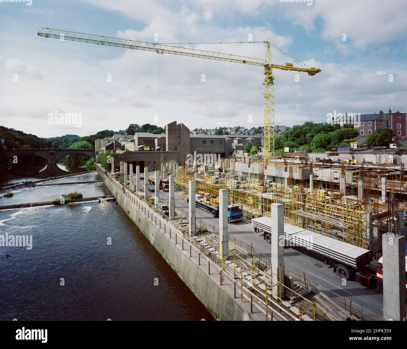 Millburngate, Durham, County Durham, 08/08/1985. Blick von der Milburngate Bridge nach Südwesten auf den Bau von Millburngate, mit einem Turmkran vor der ersten Etappe des Zentrums. Der Bau der zweiten Phase von Millburngate begann im August 1984. Phase I, die auf diesem Foto jenseits der Baustelle gezeigt wurde, wurde 1974 entwickelt; Phase II würde das Zentrum von 102.000 Quadratfuß auf 187.000 Quadratfuß erhöhen. Die zweite Phase würde durch eine überdachte Fußgängerzone mit Phase I verbunden. Der fünfstöckige Komplex würde aus einem Hauptgeschoss mit Geschäften bestehen, über dem sich Lagergüter befinden, und einem großen Einkaufszentrum Stockfoto