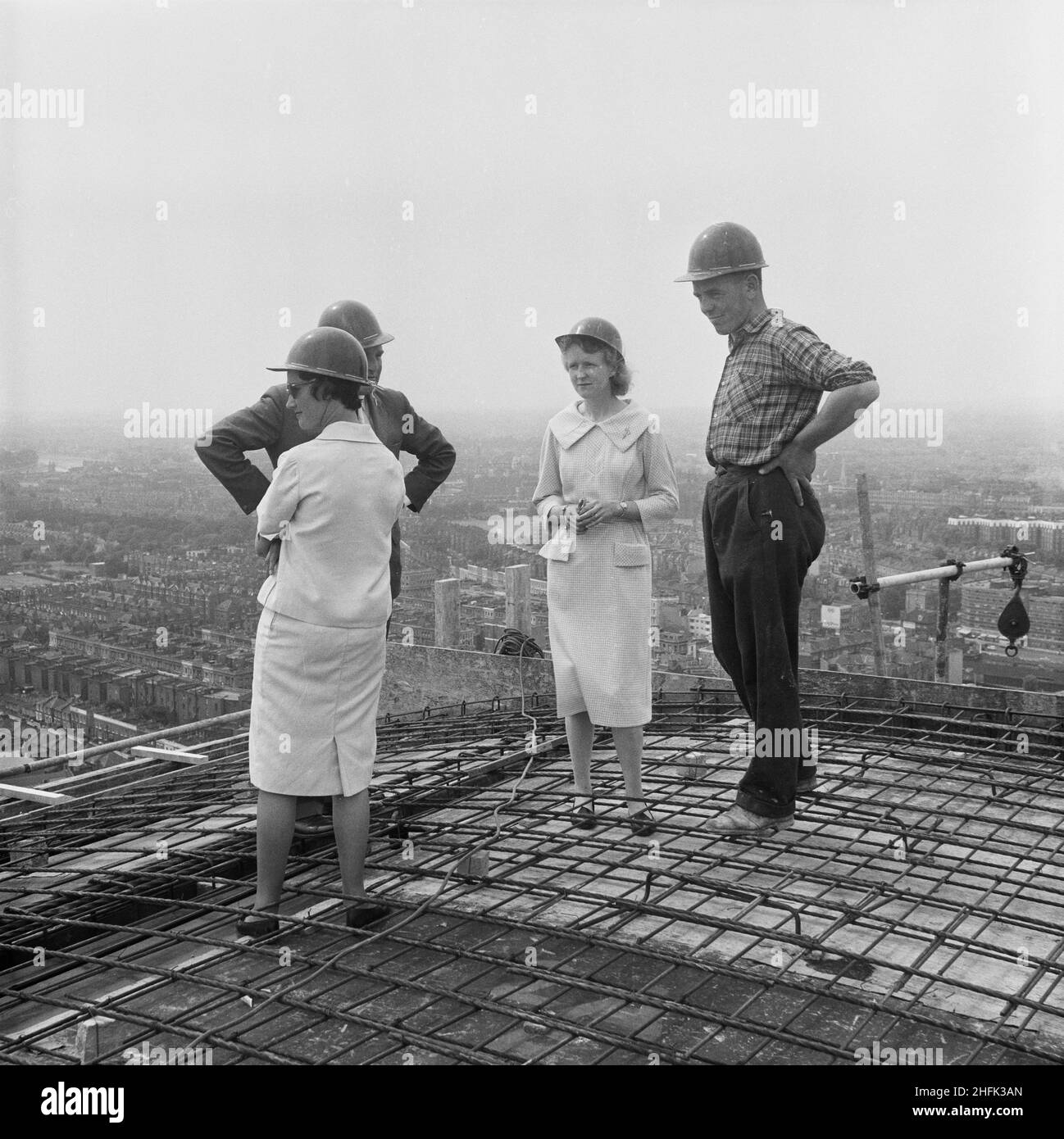 Empress State Building, Lillie Road, Earl's Court, Hammersmith und Fulham, London, 03/07/1961. Zwei Frauen mit einer Bauarbeiterin und einem Manager versammelten sich auf dem Dach des Empress State Building, um den letzten Beton zu beobachten. Laing baute die Fundamente und den Stahlbetonrahmen des Gebäudes, die Arbeiten begannen im November 1959 und liefen bis Juli 1961. Die Gruppe wurde auf dem Dach versammelt, um den letzten Betonguss zu beobachten, um das Projekt abzuschließen. Stockfoto