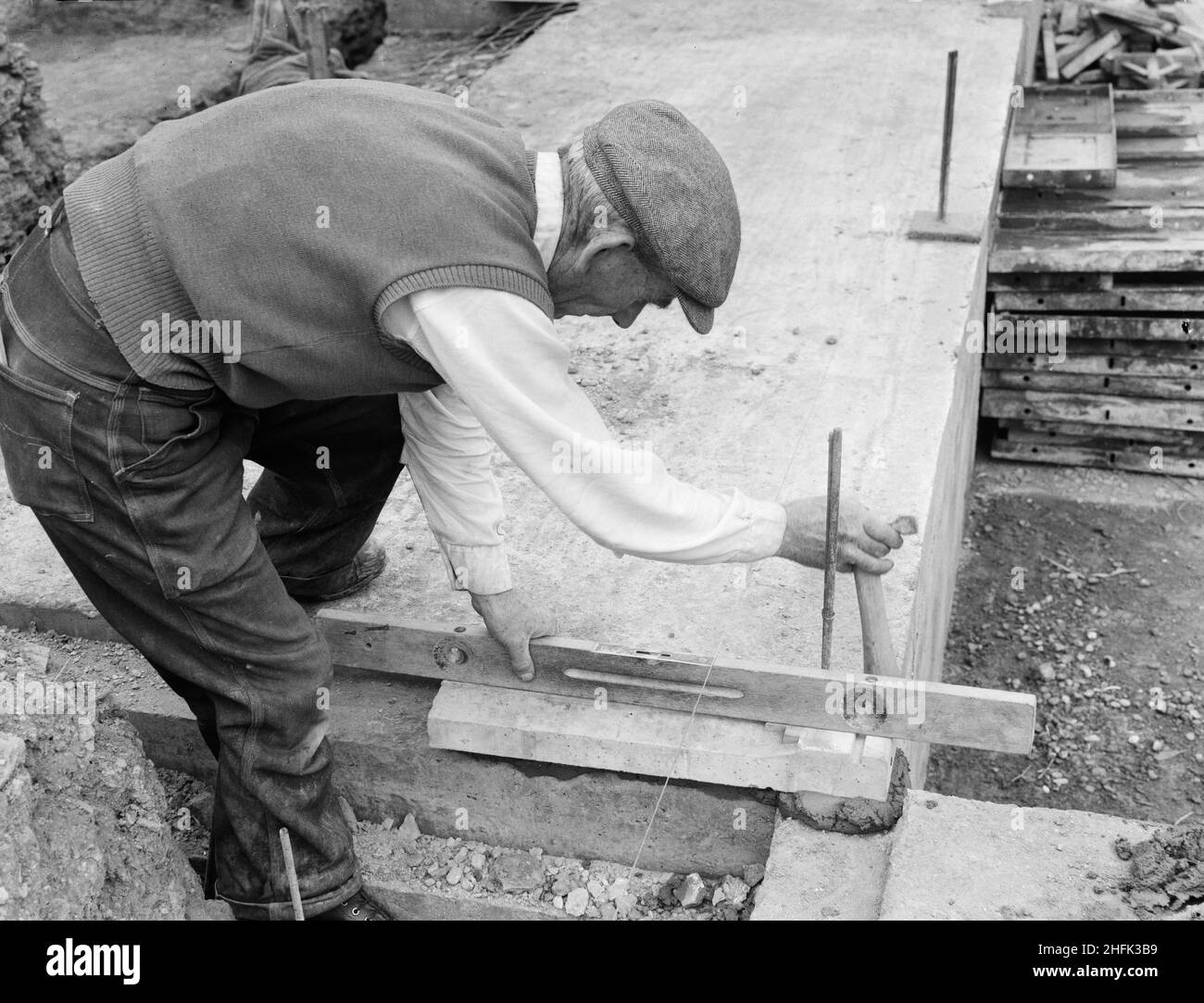 County High School, Gedling Road, Arnold, Gedling, Nottinghamshire, 30/08/1958. Ein Arbeiter, der während des Baus der Arnold County High School mit einer Wasserwaage eine Betonfundament-Platte für eine Laingspan-Wand legte. Die Arbeiten auf dem Gelände begannen im März 1958 und die Bauarbeiten für das neue Schuljahr im September 1959 wurden abgeschlossen. „Laingspan“ war ein flexibles modulares System aus Rahmenkonstruktion, das aus vorgespannten Betonfertigteilen bestand. Laing entwickelte das System in Zusammenarbeit mit der Architects and Buildings Branch des Bildungsministeriums und dem beratenden Ingenieur AJ Harris. The Arn Stockfoto