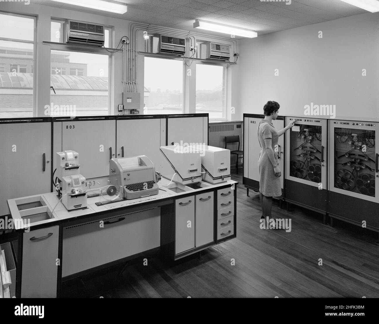Parson's Field House, Durham University, Durham, County Durham, 29/10/1964. Ein Computerraum in der Mathematikabteilung der Universität Durham, in dem eine Frau die Steuerung einer Maschine mit Bandspulen steuert. Zwischen 1963 und 1964 baute die Northern Region of Laing's Construction Company für die Durham University einen Gebäudekomplex aus Chemie, Geologie und einem Gebäude aus Mathematik, der auf Karten als „Science Laboratories“ dargestellt ist. Stockfoto