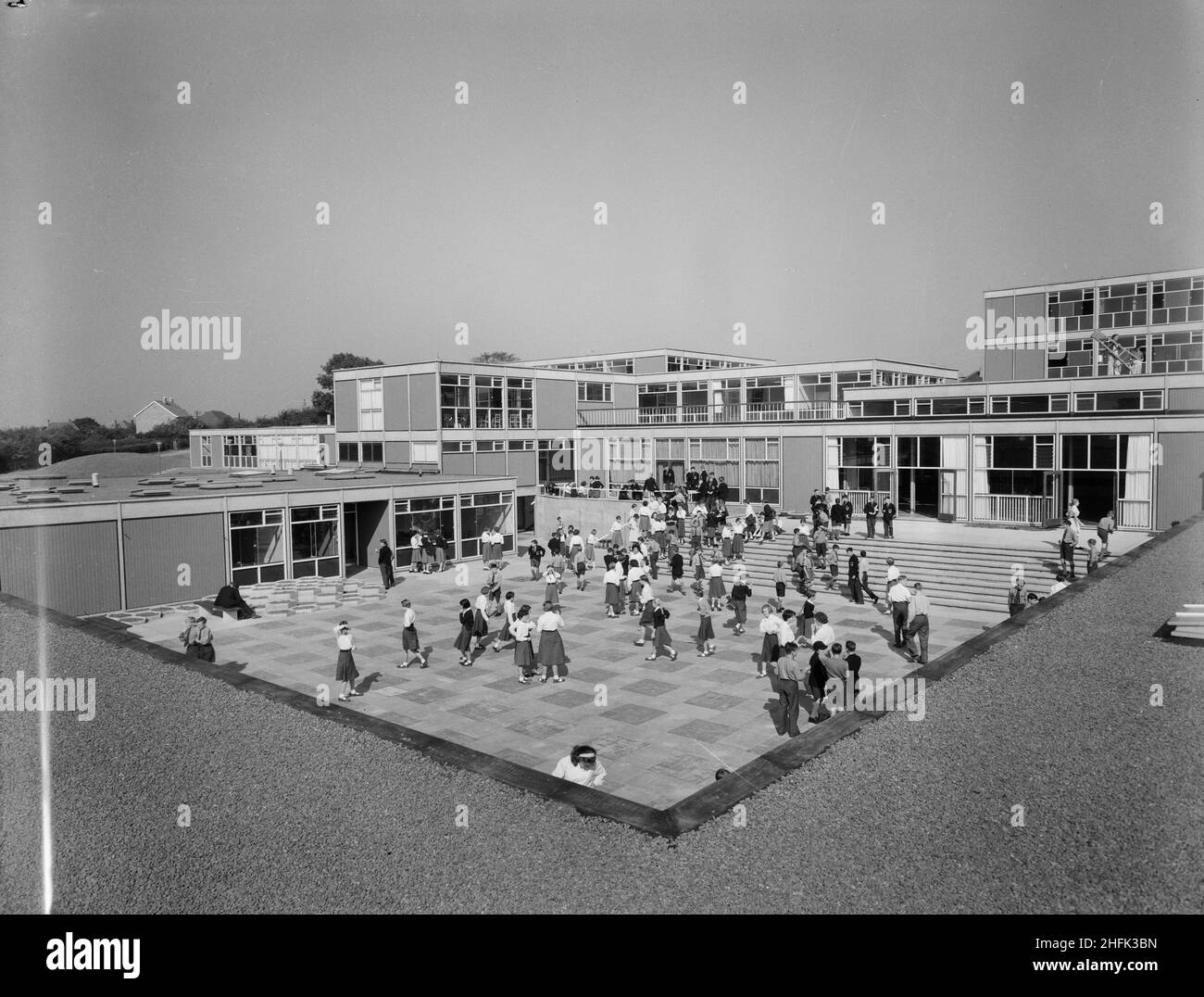 County High School, Gedling Road, Arnold, Gedling, Nottinghamshire, 11/09/1959. Ein Blick auf den Haupthof der Arnold County High School voller Schulkinder, vom Dach des "Hausblocks" nach Südosten gesehen. Die Schule Betrieb ein Häusersystem aus drei Häusern für sportliche, schulische und soziale Aktivitäten. In dem „Hausbau“, der den zentralen Innenhof auf drei Seiten umgab, waren Räume für Hausmeister, Schüler-Esszimmer und Küchen untergebracht. Dieses Foto wurde in der Oktober 1959-Ausgabe von Team Spirit, dem Laing-Unternehmensnewsletter, in einer Geschichte vorgestellt, die die des Projekts dokumentiert Stockfoto