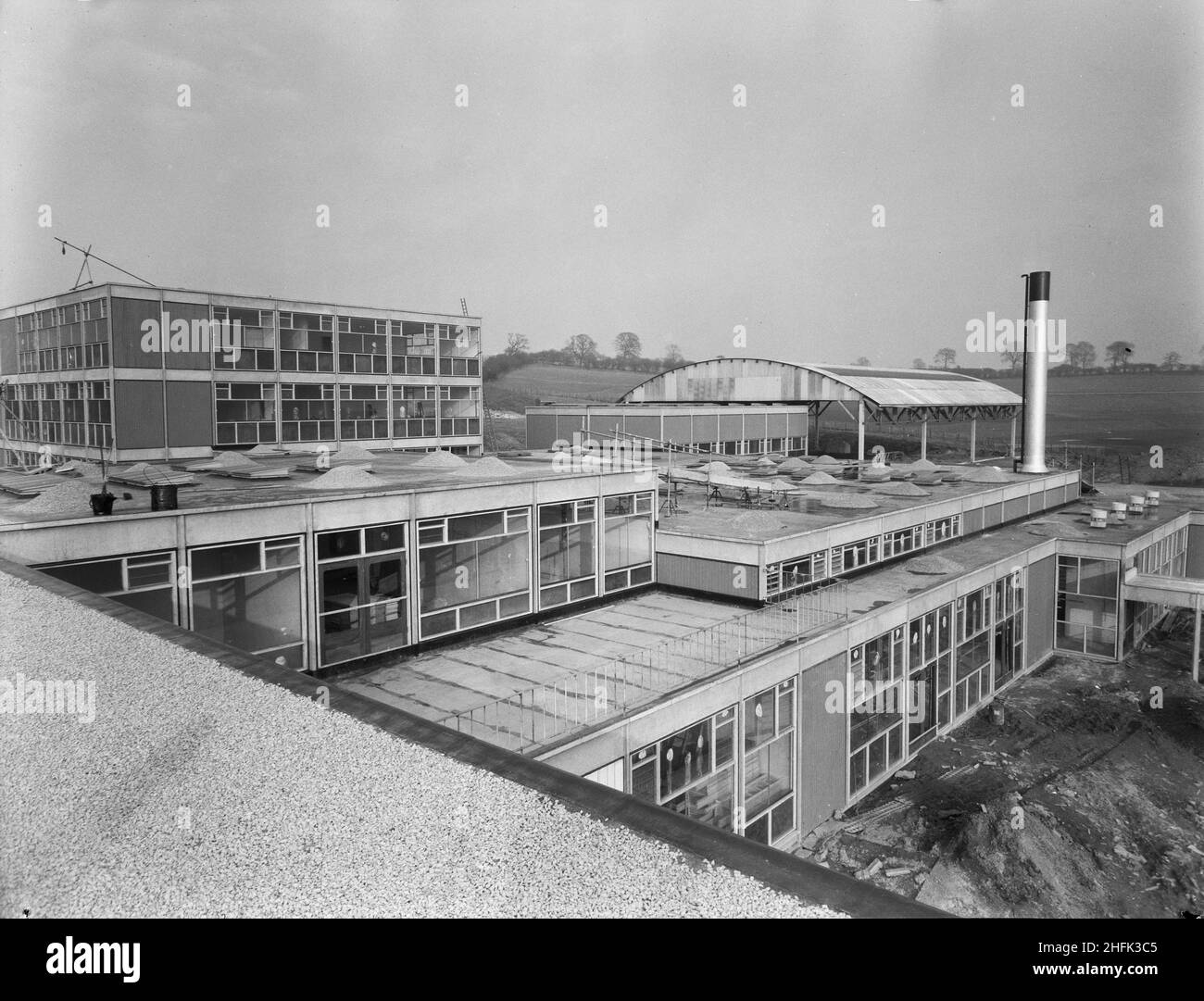 County High School, Gedling Road, Arnold, Gedling, Nottinghamshire, 23/02/1959. Ein Blick vom Dach der Arnold County High School auf den Wissenschaftsblock und den überdachten Sportplatz mit „Scheune-Dach“. Während das Gymnasium in der Schule vergleichsweise klein war, war es mit einem überdachten Außenbereich von 8.000 Quadratfuß für die Spielpraxis ausgestattet. Dieser Bereich wurde mit einer gebogenen Struktur aus Wellblech im 'Dutch Barn'-Stil überdacht, aber ansonsten nach außen hin offen. Stockfoto