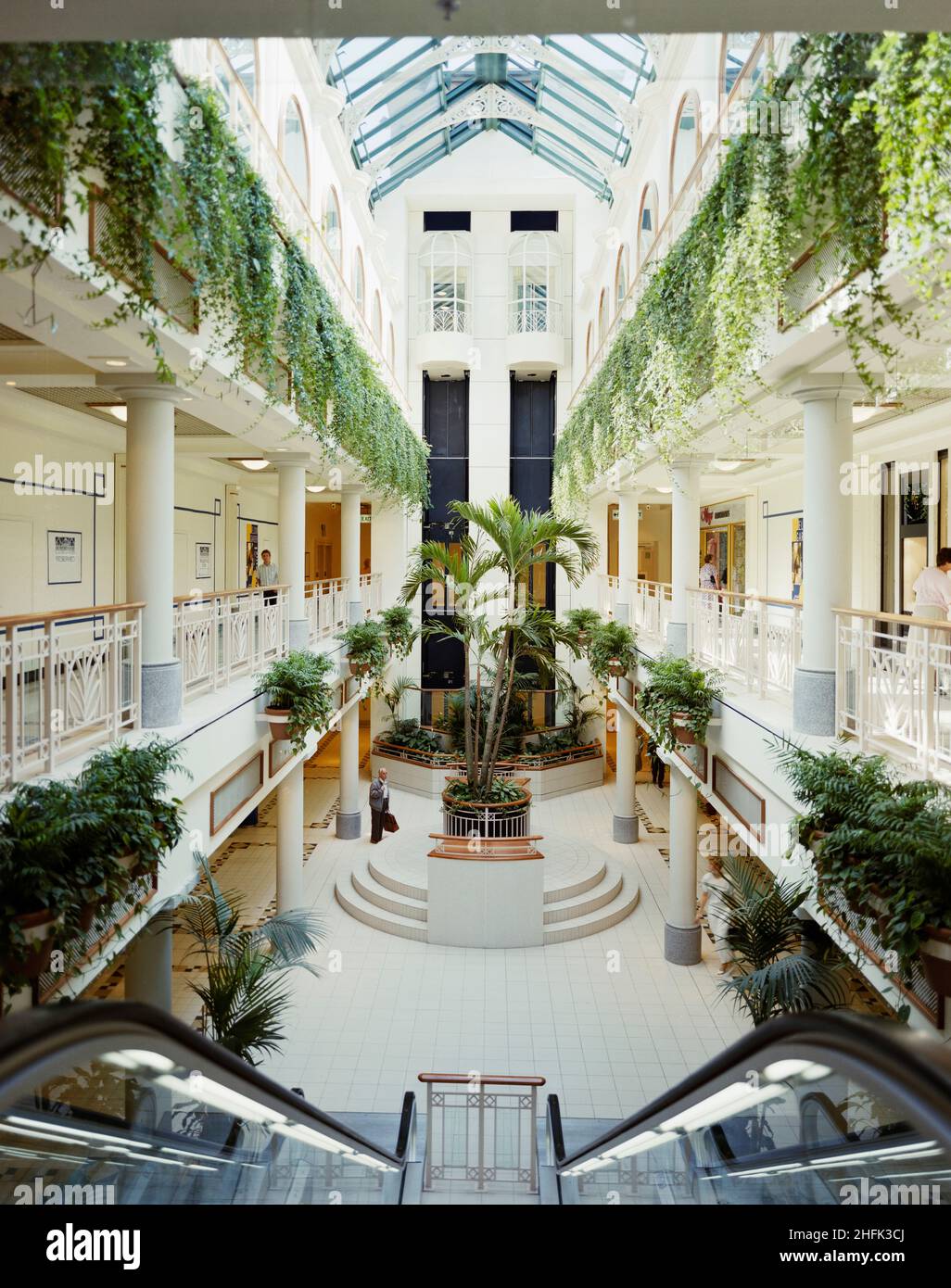 Einkaufszentrum Eldon Garden, Percy Street, Newcastle upon Tyne, 03/07/1989. Das zentrale, dreistöckige Atrium des Einkaufszentrums im Eldon Garden, von der Oberseite einer Rolltreppe aus, zeigt Palmen und Pflanzen, die von Balkonen abgesäumt sind. Das Einkaufszentrum Eldon Garden bestand aus 42 Geschäften auf 3 Stockwerken und einem Parkplatz mit 477 Stellflächen. Laing sicherte sich den &#XA3;11,5m Managementvertrag für den Bau im Jahr 1987 für Greycoat Shopping Plc. Die Arbeiten begannen im Januar 1988 und das Zentrum war ab März 1989 für die Öffentlichkeit zugänglich und im November 1989 offiziell von Prinzessin Margaret eröffnet. Die Entwicklung Stockfoto