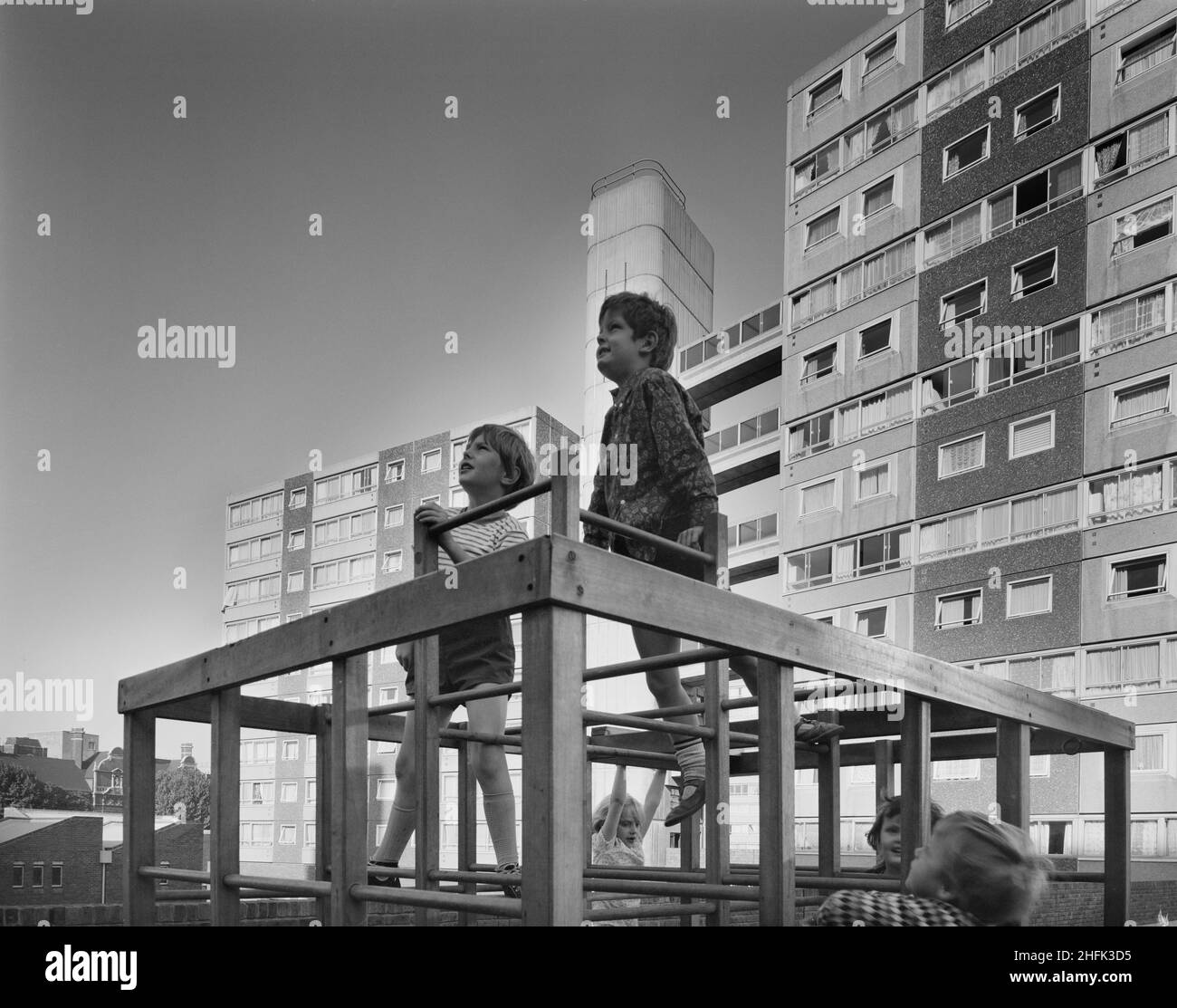 Doddington Estate, Battersea, Wandsworth, London, 08/09/1971. Kinder spielen auf einem Klettergerüst auf dem Doddington Estate, hinter dem ein 10-stöckiges und 13-stöckiges Wohngebäude steht, das mit dem 12M Jespersen-System gebaut wurde. Das Doddington Estate, direkt an der Battersea Park Road, wurde von den Architekten Emberton, Tardrew &amp; Partners entworfen. Das Anwesen, zu dem auch Wohntürme gehörten, wurde zwischen 1967-71 von Laing für den Wandsworth London Borough Council erbaut. Es wurde mit ihrem 12M Jespersen-Bausystem gebaut, das aus vorgefertigten Teilen und Betonfertigteilen besteht, die auf ihrem Beton hergestellt wurden Stockfoto