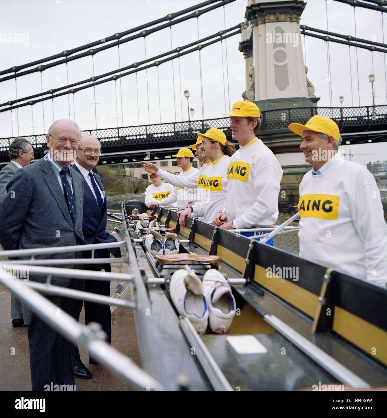 British Rowing, Lower Mall, Hammersmith, Hammersmith und Fulham, London, 01/03/1994. Sir Maurice Laing und Martin Brandon-Bravo, der Präsident der Amateur Rowing Association, mit einer Crew in Laing-Hüten und Sweatshirts und ihrem Boot vor der Hammersmith Bridge. Anlass war der Start einer Sponsoring-Kampagne zur Unterstützung des britischen Ruder. Laing würde für die Vorbereitung der Athleten auf die Olympischen Spiele 1996 in Atlanta 115.000;XA3#in drei Saisons bereitstellen. Stockfoto