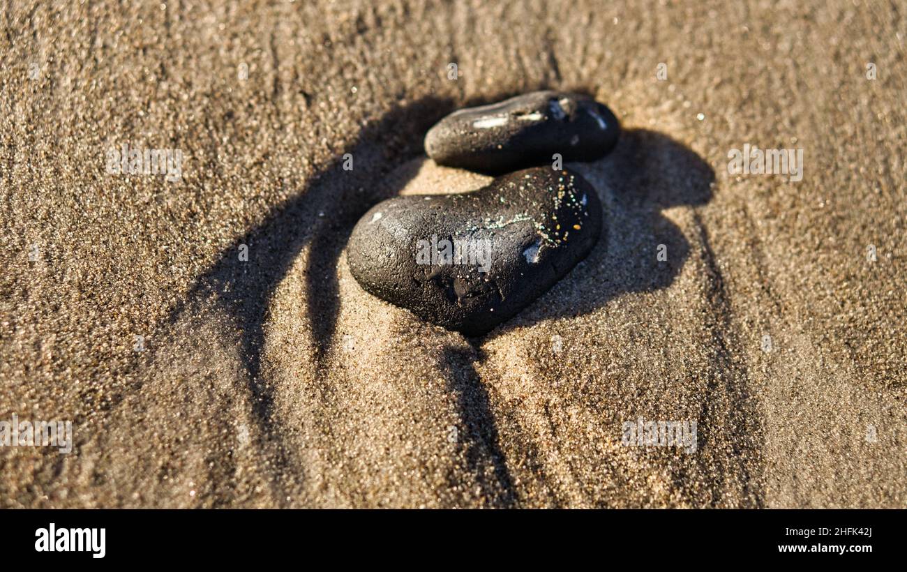 Herzförmiger Stein im Sand des Strandes an der Ostsee. Romantisches Symbol für Verliebte. Kleines Zeichen als Stillleben. Stockfoto