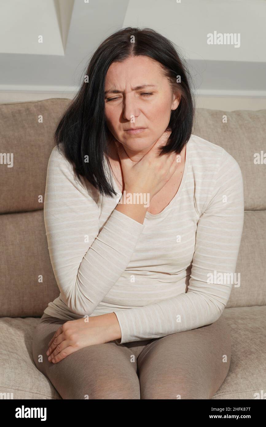 Reife Frau, die ihren Hals berührt. Kranke Frau fühlt Halsschmerzen, Husten, Pharyngitis und Heiserkeit. Schilddrüsenerkrankung. Medizinische und medizinische Versorgung. Stockfoto