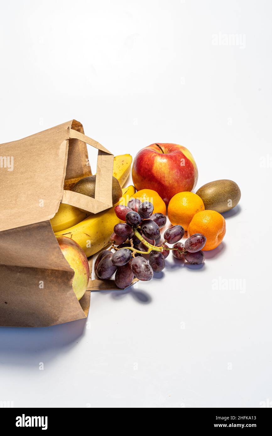 Einkaufen und Lieferung von gesunden Lebensmitteln auf weißem Hintergrund. Gesundes veganes vegetarisches Essen in einer Papiertüte. Gesunde Ernährung gegen Covid Stockfoto