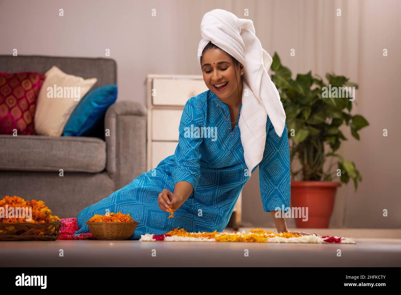 Indische Dame wickelte ihr nasses Haar mit einem Handtuch und dekorieren Boden mit Blumen während des Festivals Stockfoto
