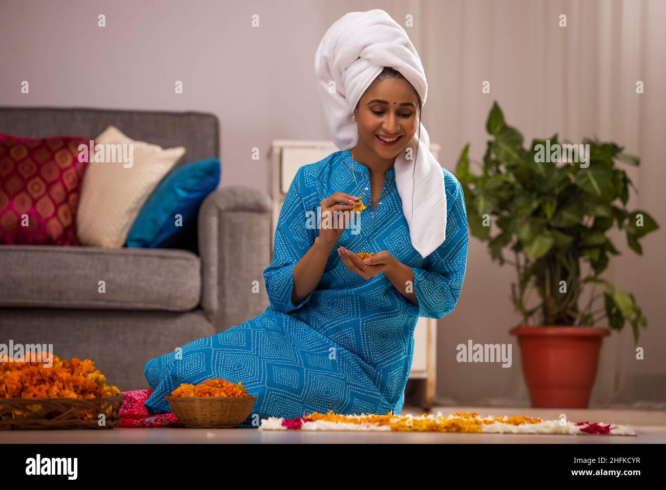 Indische Frau wickelte ihr nasses Haar mit einem Handtuch und dekorieren Boden mit Blumen während des Festivals Stockfoto