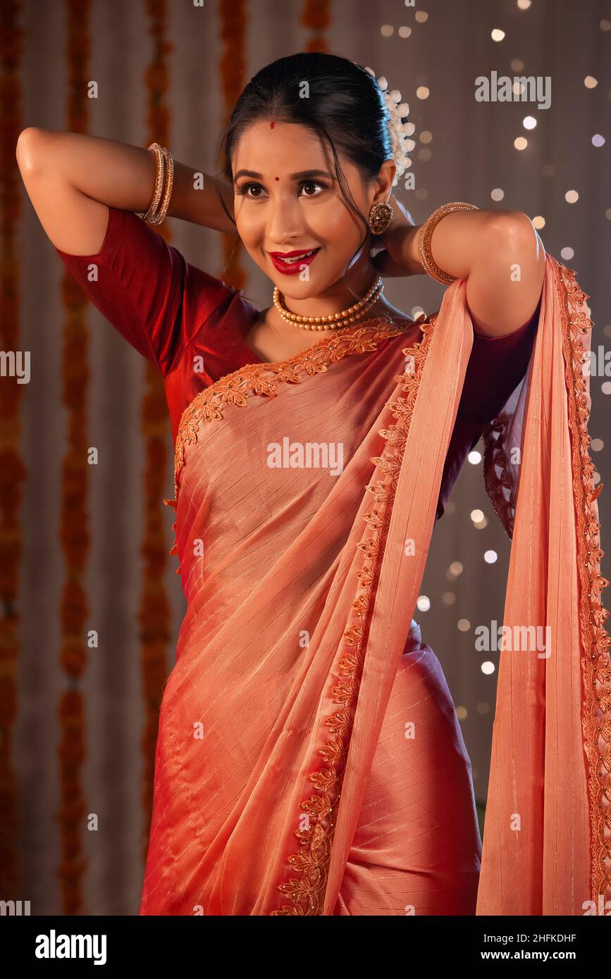 Eine wunderschöne Frau, die in einer Perlenkette steht und lächelt, inmitten von diwali-Dekorationen und Lichtern. Stockfoto