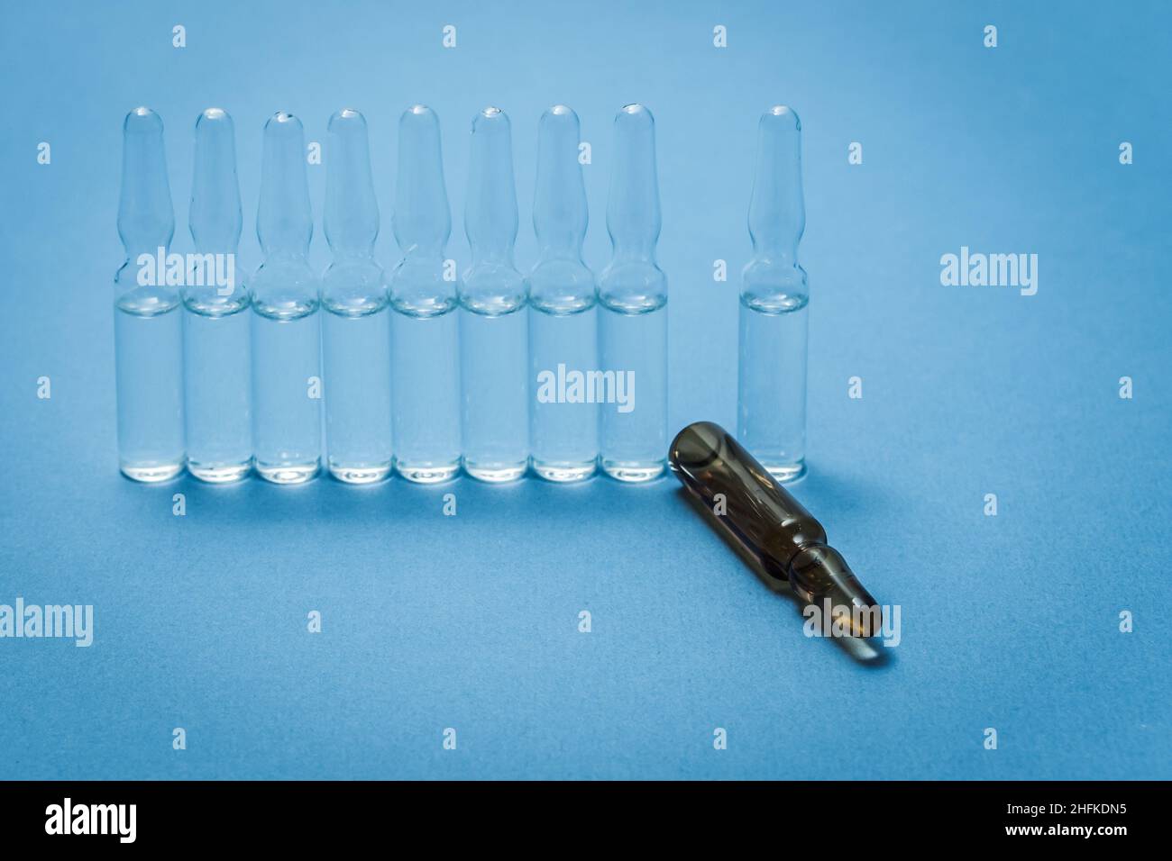 Medizinische Ampullen stehen auf dem Tisch, eine davon in einer anderen Farbe. Stockfoto