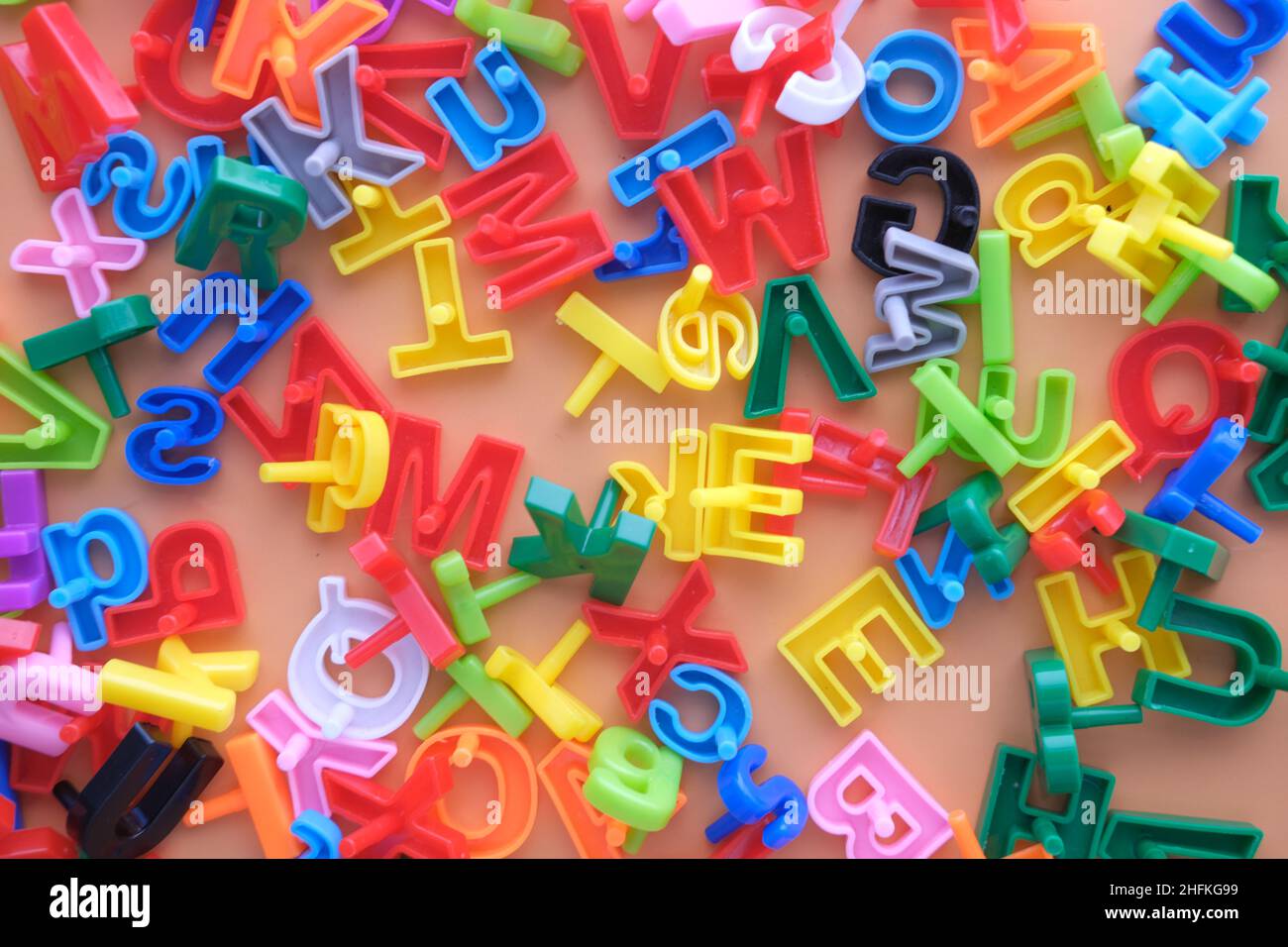 Bunte Plastikbuchstaben auf orangefarbenem Hintergrund, Draufsicht Stockfoto