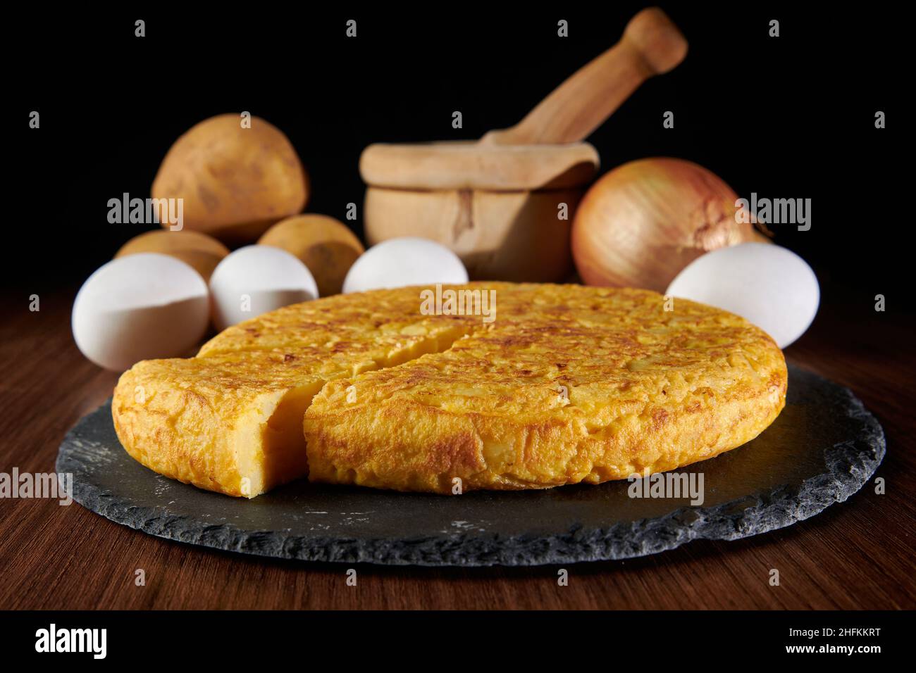 Eine Nahaufnahme eines frischen leckeren spanischen Omelettes und die Zutaten auf dem Hintergrund, ein traditionelles Gericht aus Spanien Stockfoto