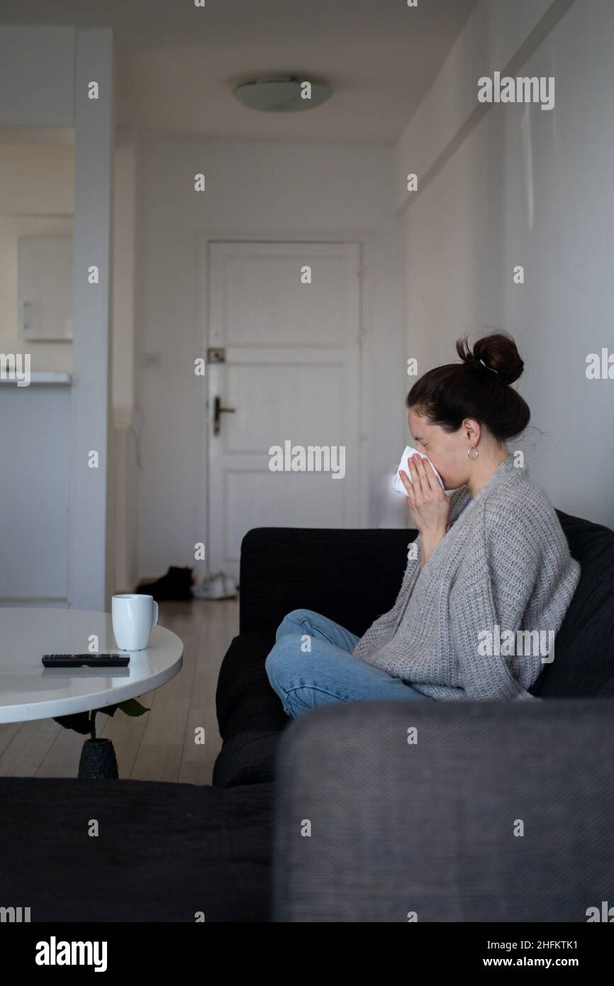Eine kranke Frau hat eine laufende Nase, niest und bleibt zu Hause. Isolationszeit der Quarantäne Stockfoto