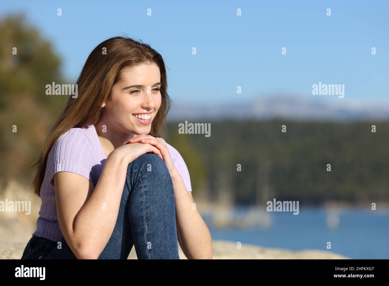 Glückliche Frau, die Aussicht in einem wunderschönen See betrachtet Stockfoto
