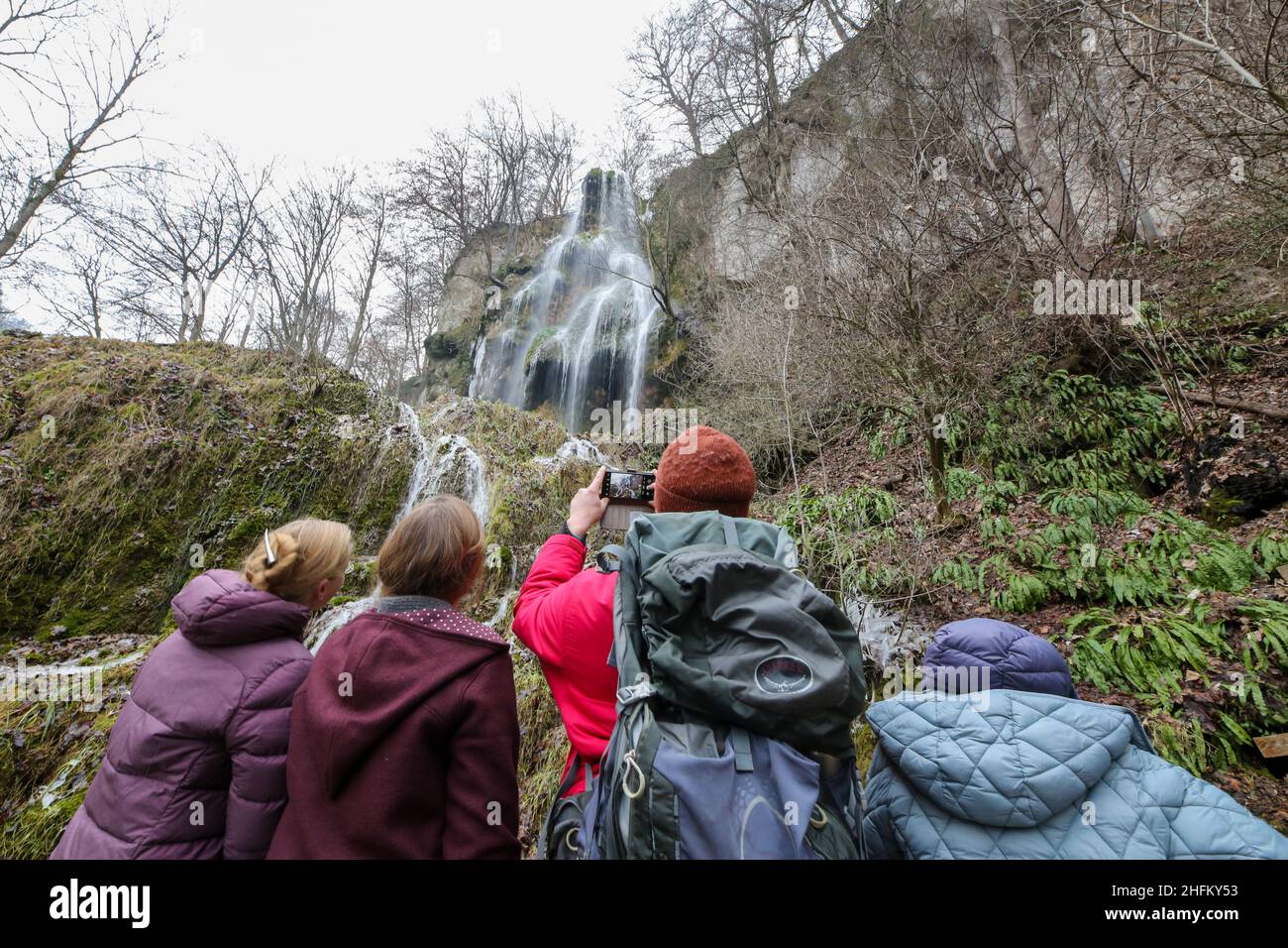 Bad Urach, Deutschland. 16th Januar 2022. Wanderer stehen unter dem Wasserfall bei Bad Urach. Der Urach-Wasserfall gehört zu den Sehenswürdigkeiten des UNESCO-Weltgeoparks Schwäbische Alb und des von der UNESCO anerkannten Biosphärenreservats Schwäbische Alb. Quelle: Thomas Warnack/dpa/Alamy Live News Stockfoto