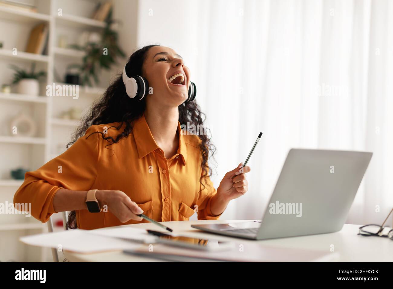 Lady Trägt Kopfhörer Spielen So, Als Ob Sie Drums Spielen Würde, Die Im Laptop Drinnen Sitzen Stockfoto