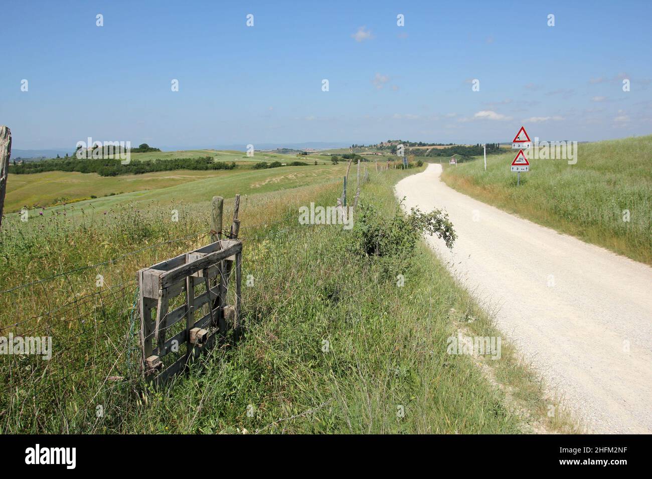 Die typischen staubigen Schotterstraßen in der Toskana in Italien mit einer schönen Natur und Landschaft rund um und alte Häuser herum. Stockfoto